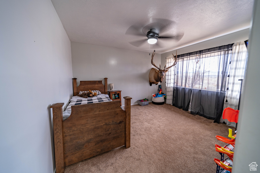Carpeted bedroom with a ceiling fan