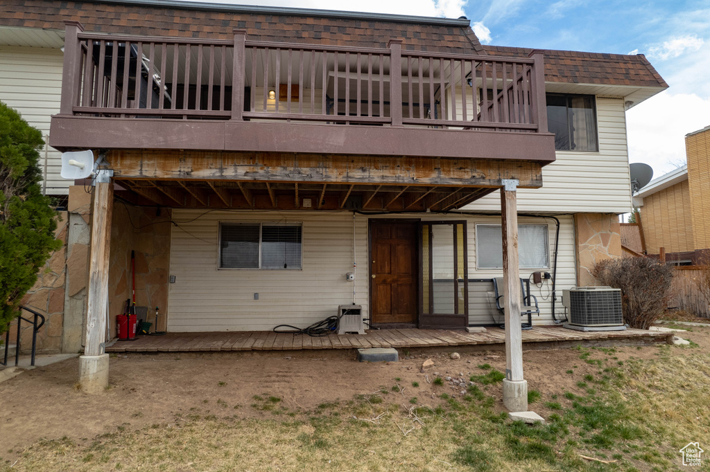 Rear view of property with a balcony, central AC, mansard roof, and a shingled roof