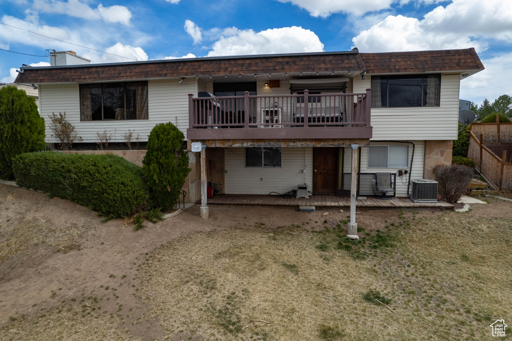 Back of property with fence, central AC, a deck, and a patio
