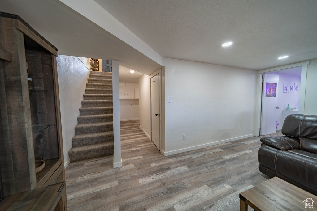 Living area with baseboards, stairs, recessed lighting, and light wood-type flooring