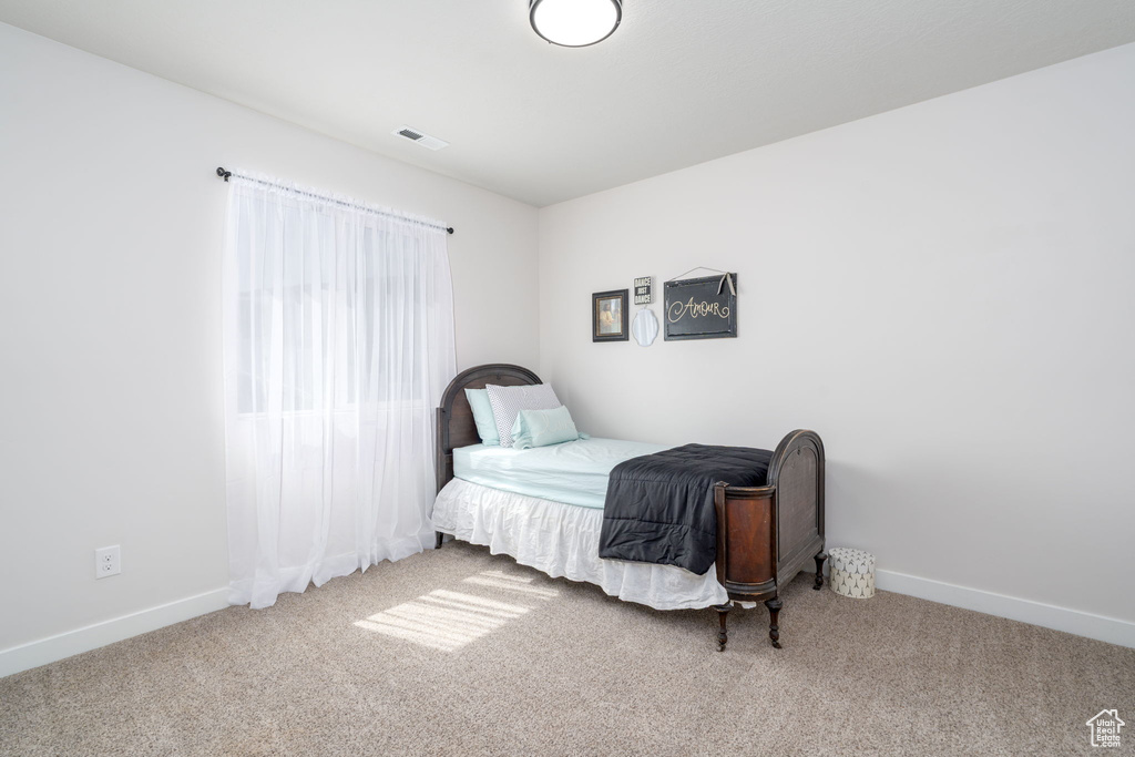 Carpeted bedroom featuring baseboards and visible vents