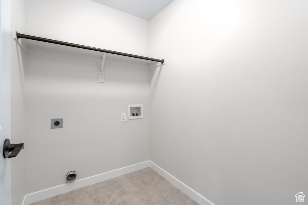 Clothes washing area featuring hookup for an electric dryer, light tile patterned floors, baseboards, laundry area, and washer hookup