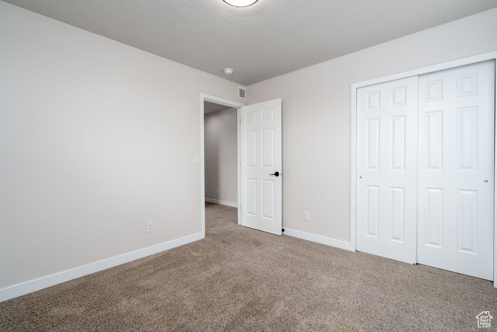 Unfurnished bedroom featuring carpet flooring, a closet, baseboards, and visible vents