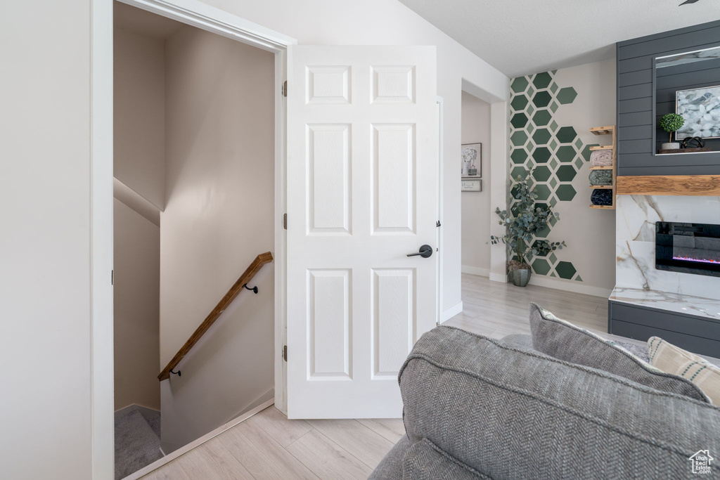 Living area with a premium fireplace, baseboards, an accent wall, wallpapered walls, and light wood-style flooring