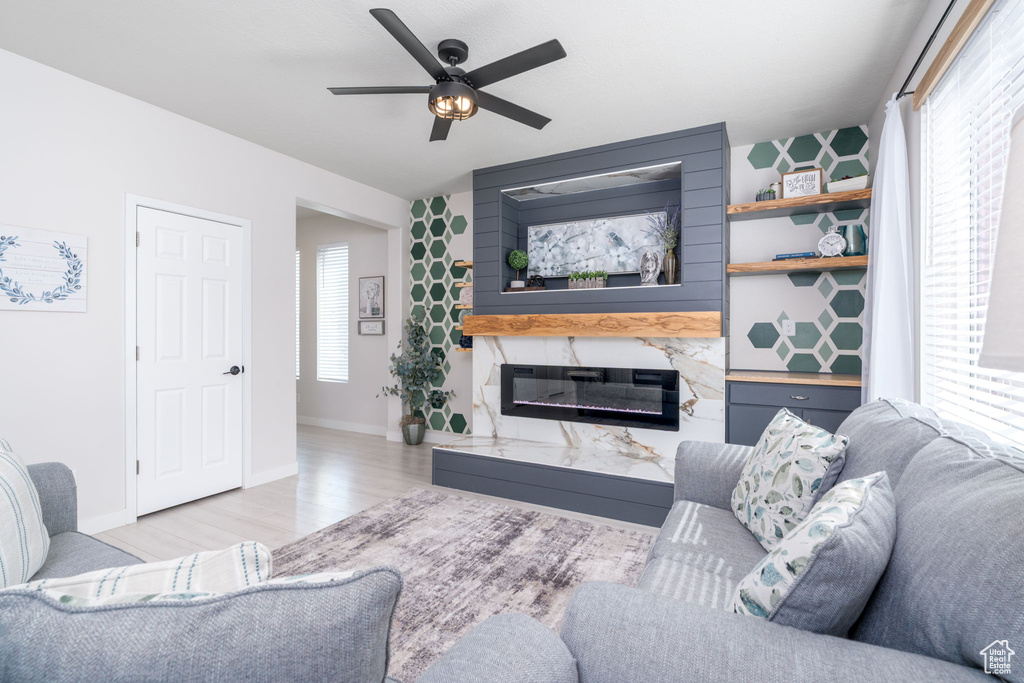 Living room featuring baseboards, a fireplace, a ceiling fan, and a healthy amount of sunlight
