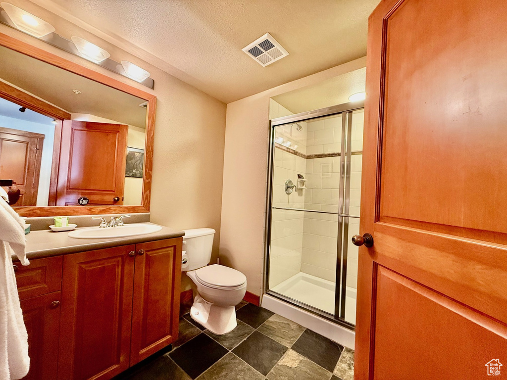 Bathroom with vanity, toilet, a shower stall, a textured ceiling, and visible vents