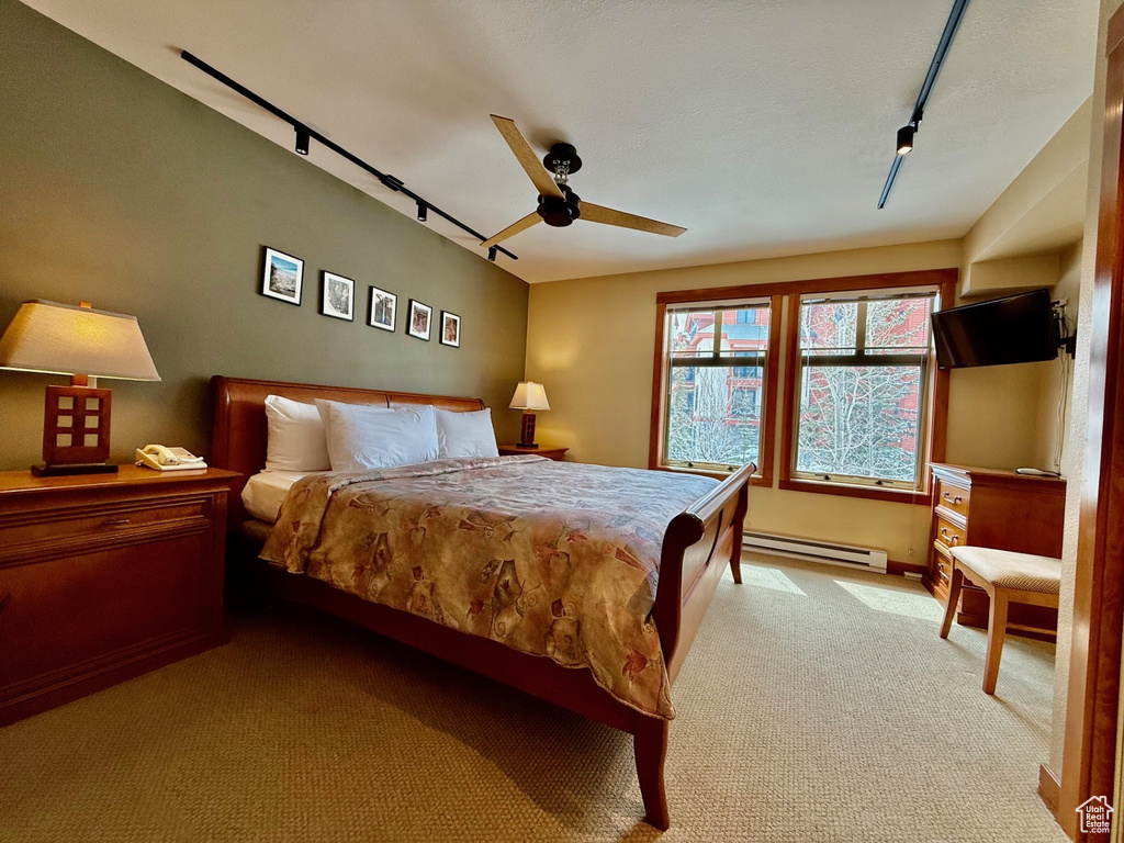 Bedroom featuring rail lighting, a baseboard heating unit, carpet, and a ceiling fan