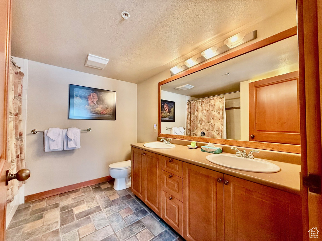 Full bathroom featuring toilet, a sink, baseboards, and visible vents