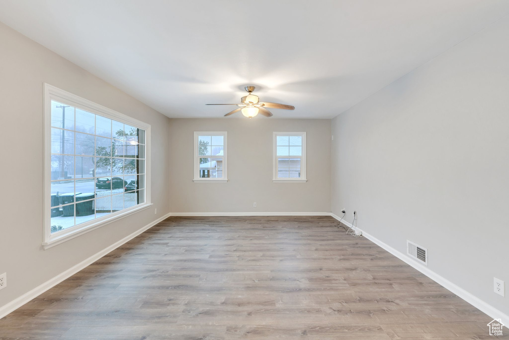 Empty room featuring baseboards, visible vents, a ceiling fan, and wood finished floors