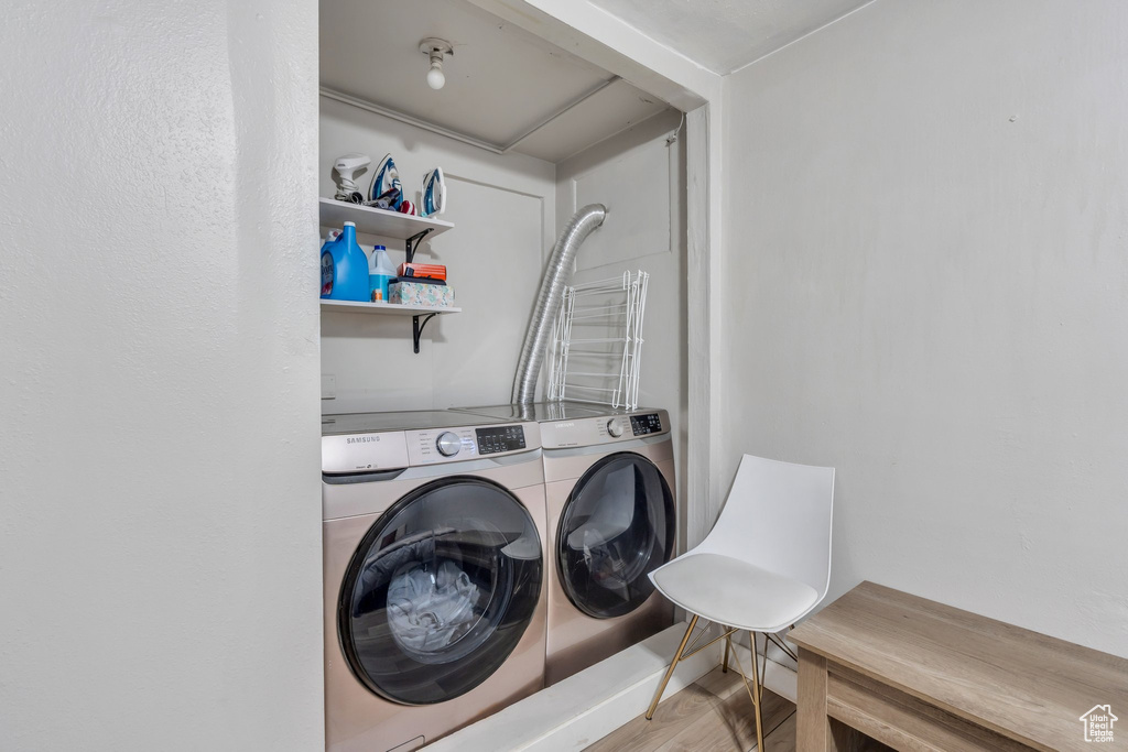 Washroom featuring washing machine and clothes dryer, wood finished floors, and laundry area