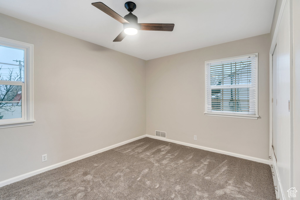 Spare room featuring baseboards, visible vents, ceiling fan, and carpet flooring