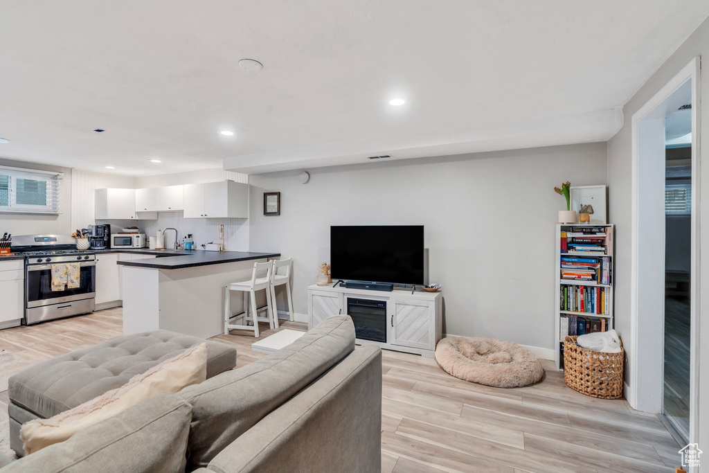 Living room with recessed lighting, baseboards, and light wood-type flooring