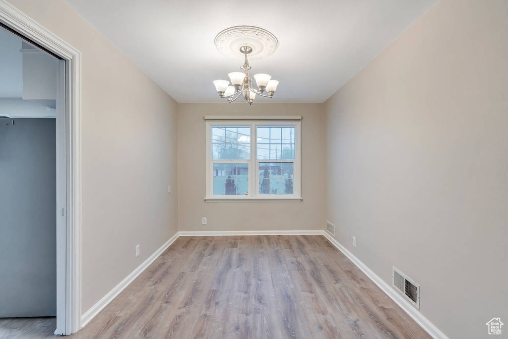 Unfurnished dining area featuring baseboards, visible vents, a chandelier, and light wood-type flooring