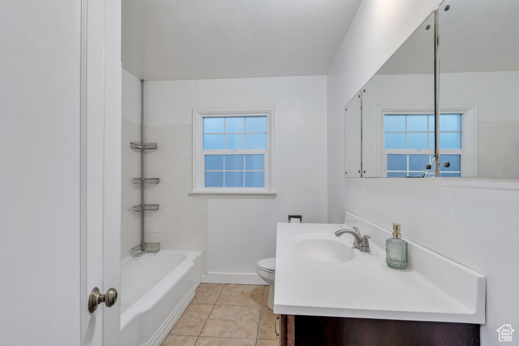 Bathroom featuring baseboards, toilet, tile patterned floors, vanity, and bathing tub / shower combination