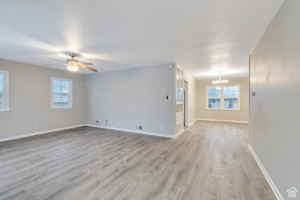 Unfurnished room with baseboards, a wealth of natural light, and light wood-style floors