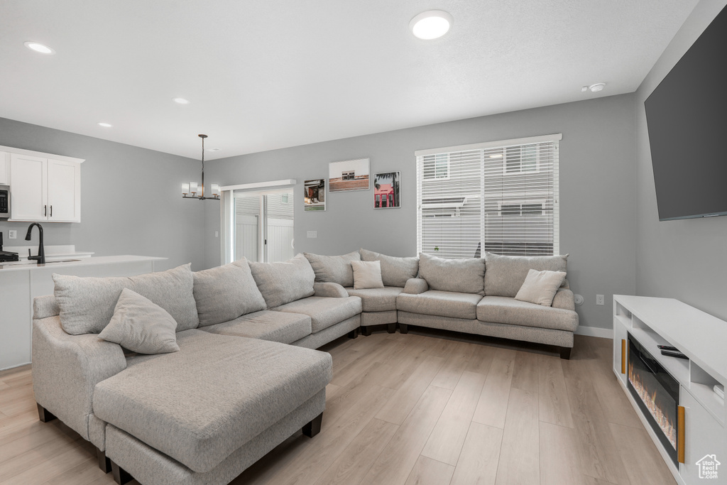 Living area with baseboards, recessed lighting, a chandelier, and light wood-style floors