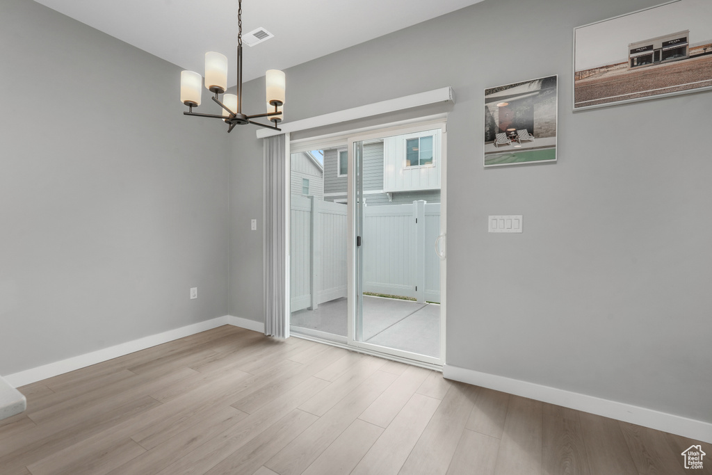 Interior space featuring baseboards, visible vents, wood finished floors, and an inviting chandelier
