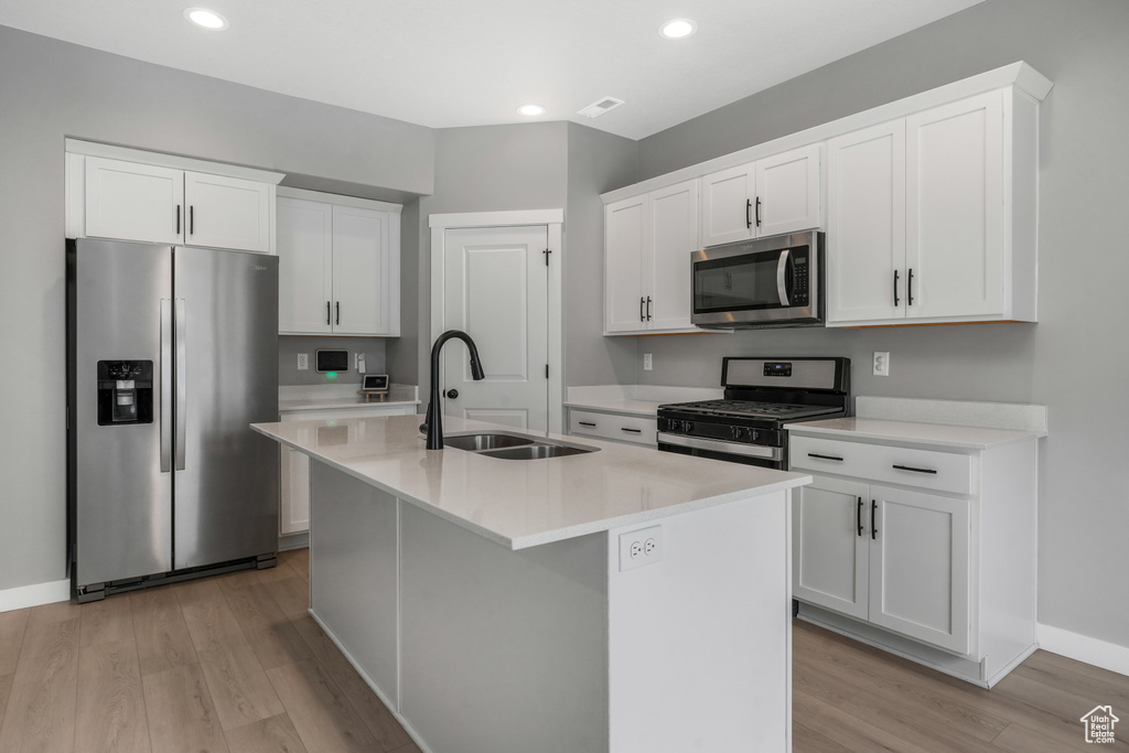 Kitchen with visible vents, light wood finished floors, a center island with sink, appliances with stainless steel finishes, and a sink