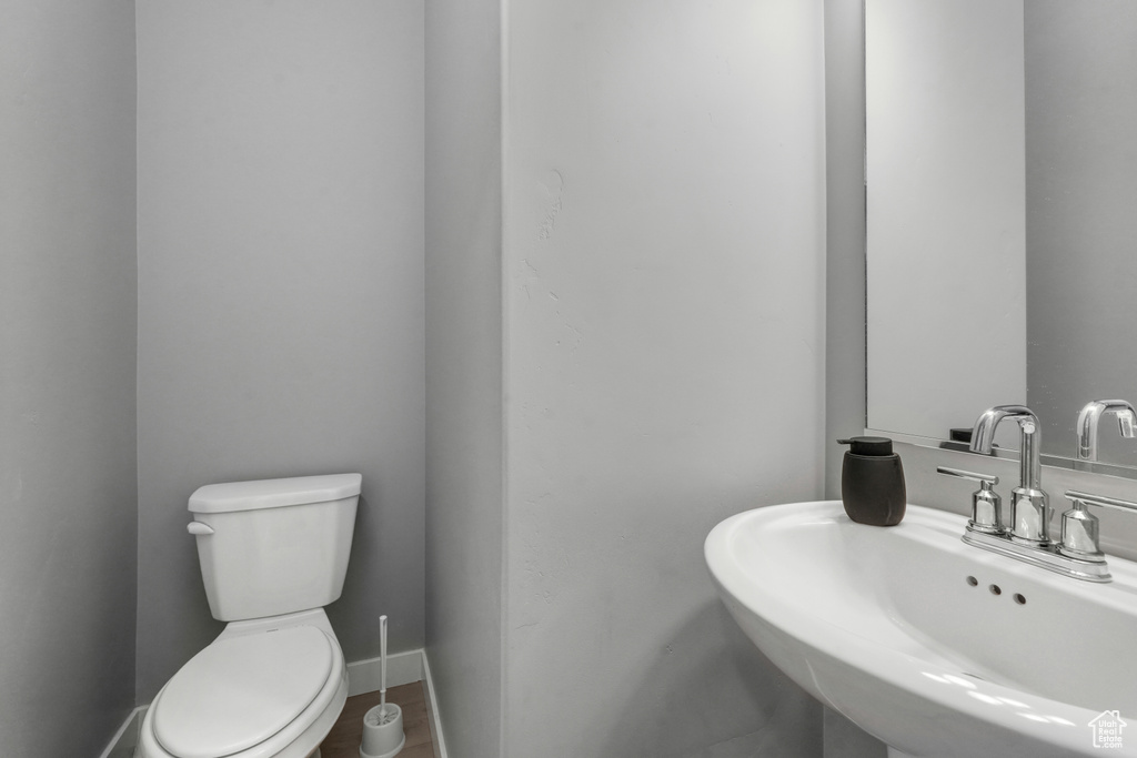 Half bathroom with baseboards, toilet, and a sink
