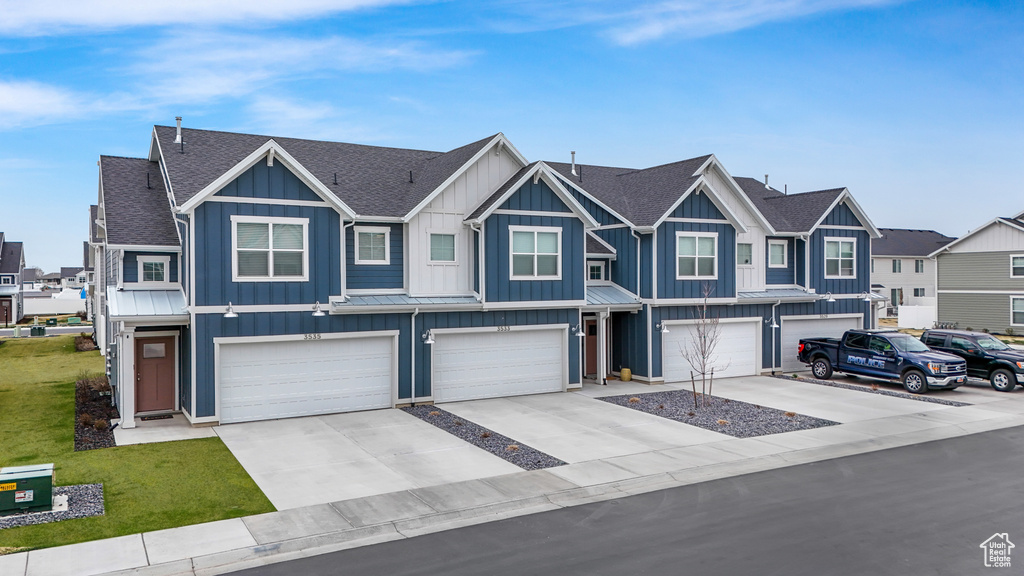 Townhome / multi-family property with driveway, board and batten siding, a residential view, a shingled roof, and a garage