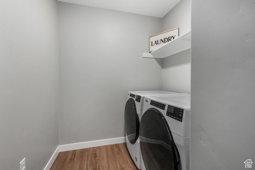 Washroom with independent washer and dryer, wood finished floors, laundry area, and baseboards