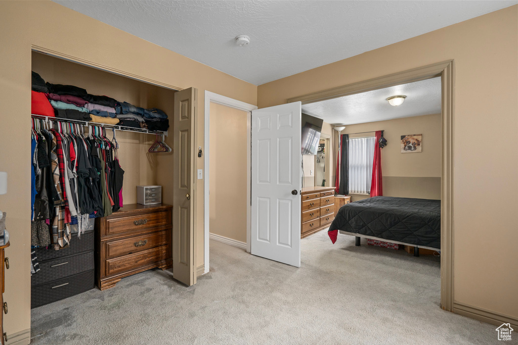 Bedroom featuring a closet, baseboards, and light carpet