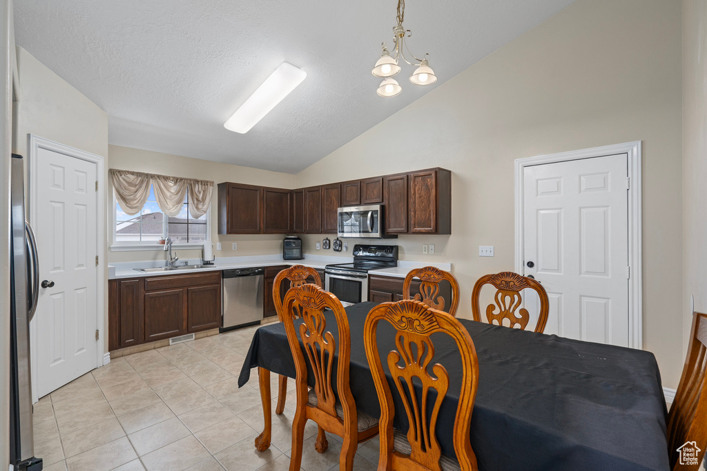 Kitchen with light countertops, lofted ceiling, stainless steel appliances, a sink, and dark brown cabinetry