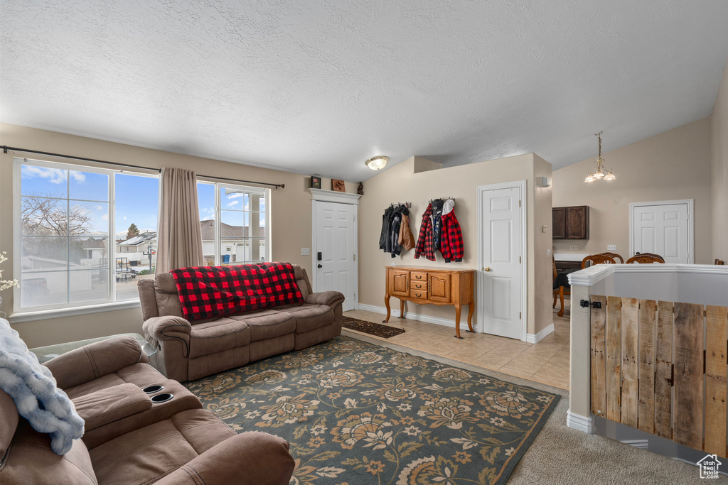 Living room featuring baseboards, a textured ceiling, vaulted ceiling, and light tile patterned floors