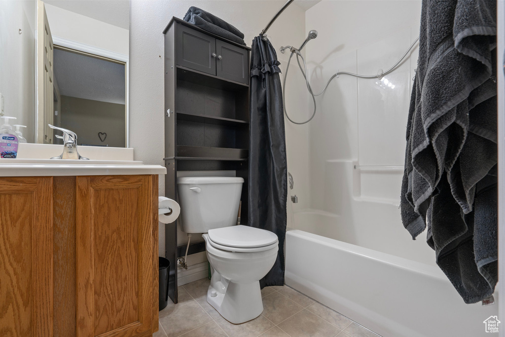 Bathroom with shower / bath combo, toilet, tile patterned floors, and vanity