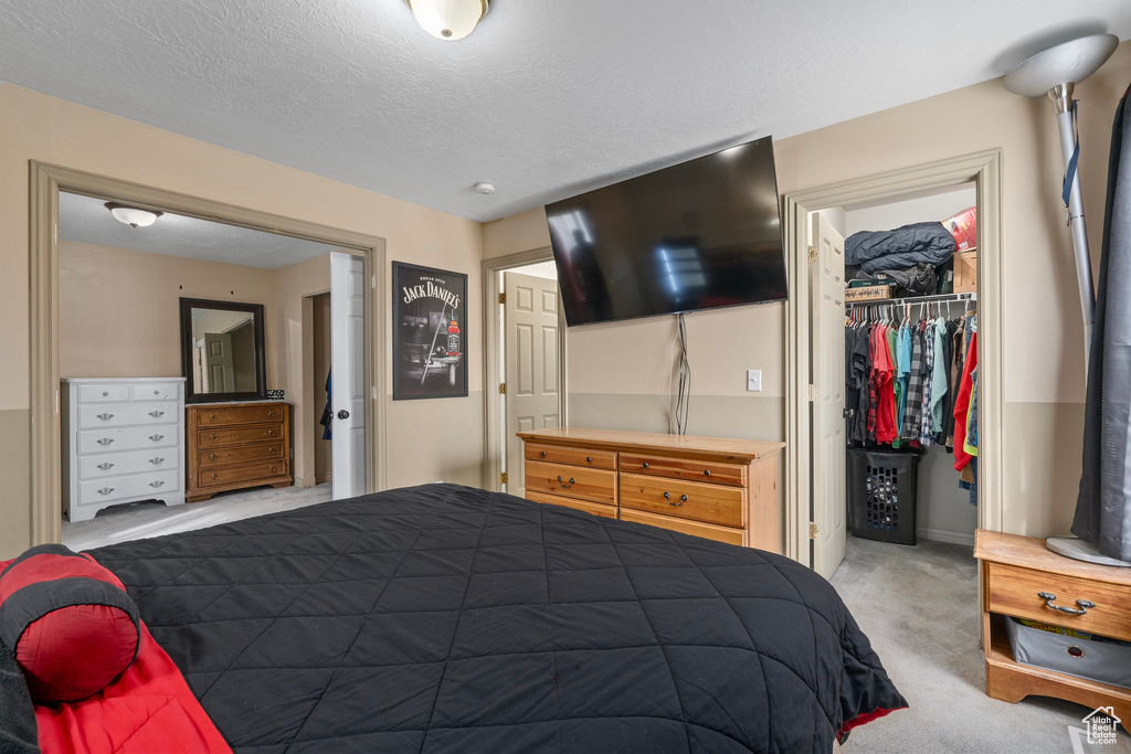 Bedroom with a closet, carpet floors, a spacious closet, and a textured ceiling