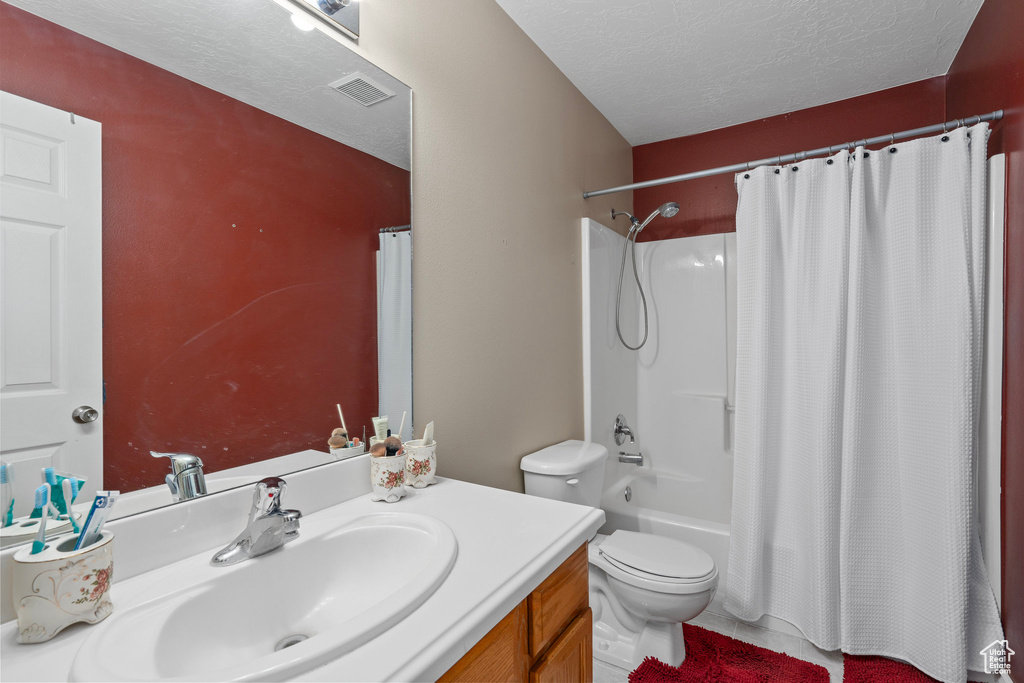 Full bathroom featuring toilet, shower / bathtub combination with curtain, vanity, a textured ceiling, and visible vents