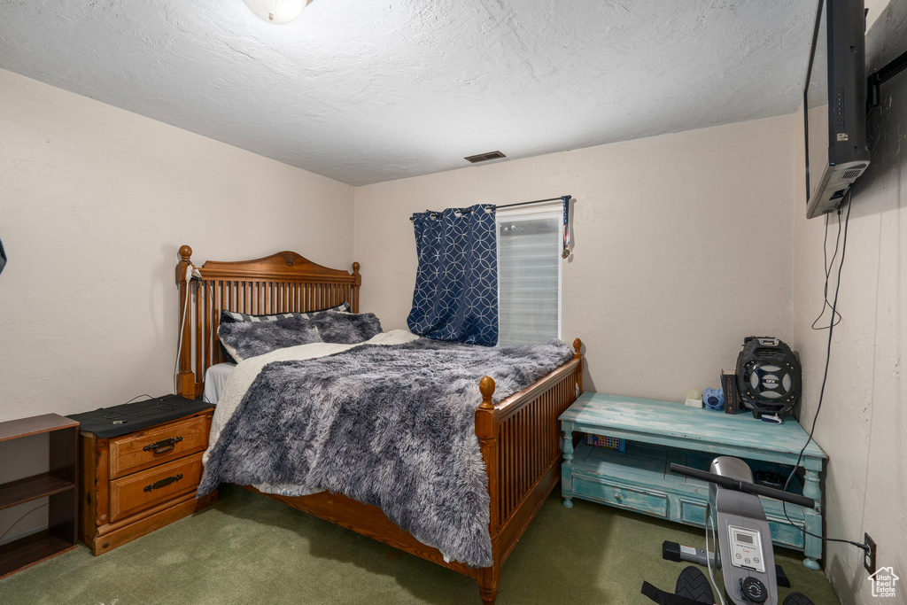 Bedroom with visible vents, carpet floors, and a textured ceiling