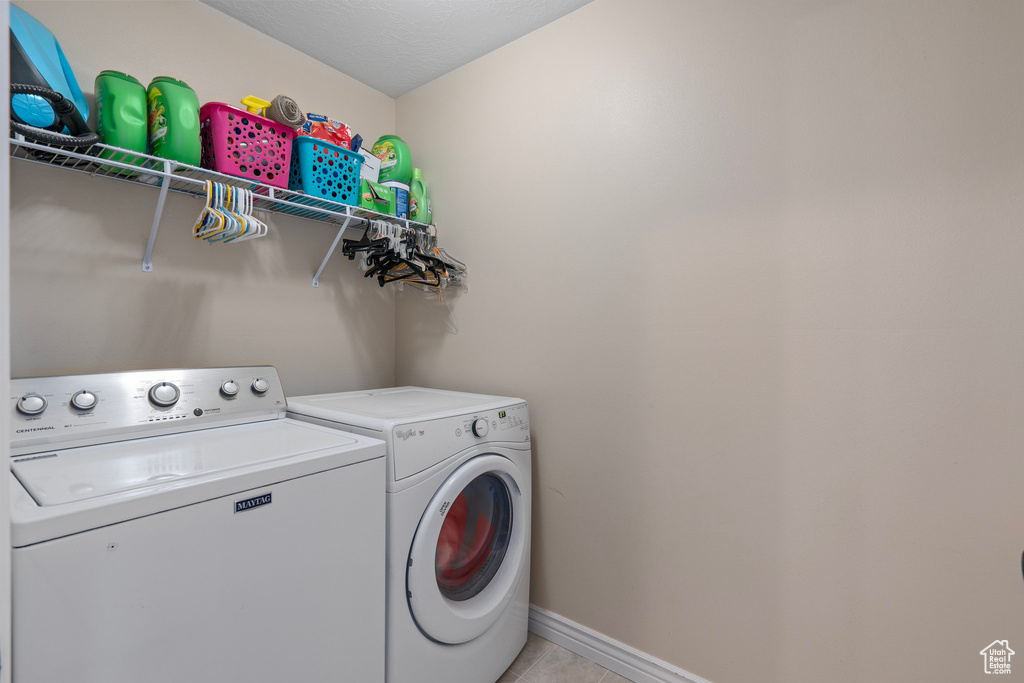 Washroom featuring light tile patterned floors, washer and clothes dryer, baseboards, and laundry area