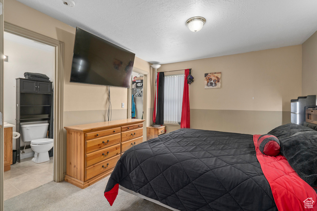 Bedroom featuring ensuite bath, a textured ceiling, and light colored carpet