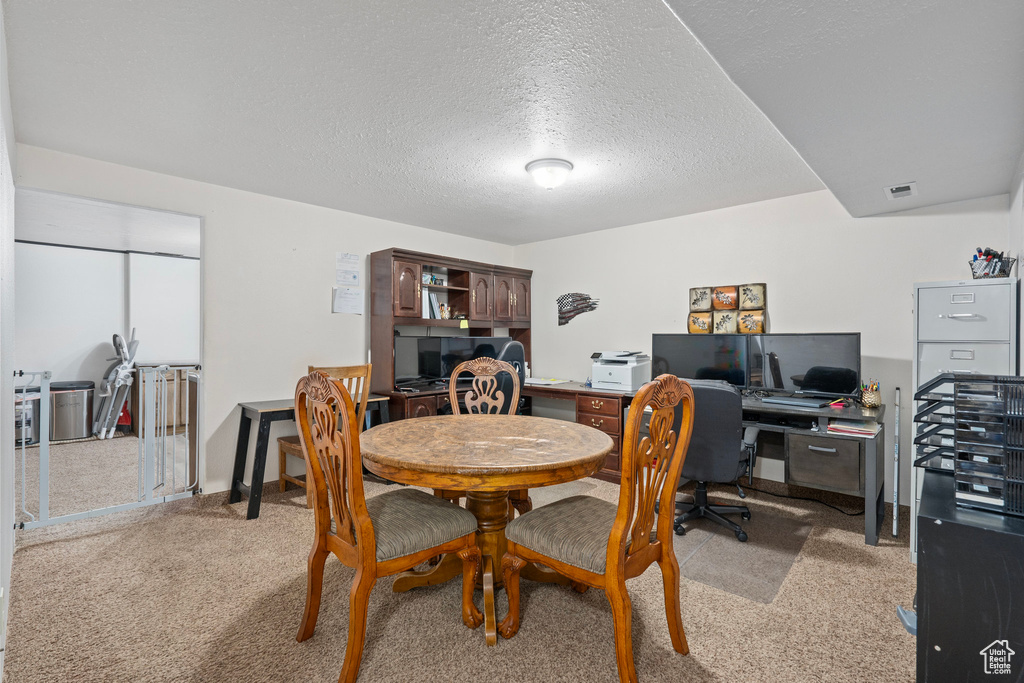 Dining room featuring a textured ceiling, light colored carpet, and visible vents