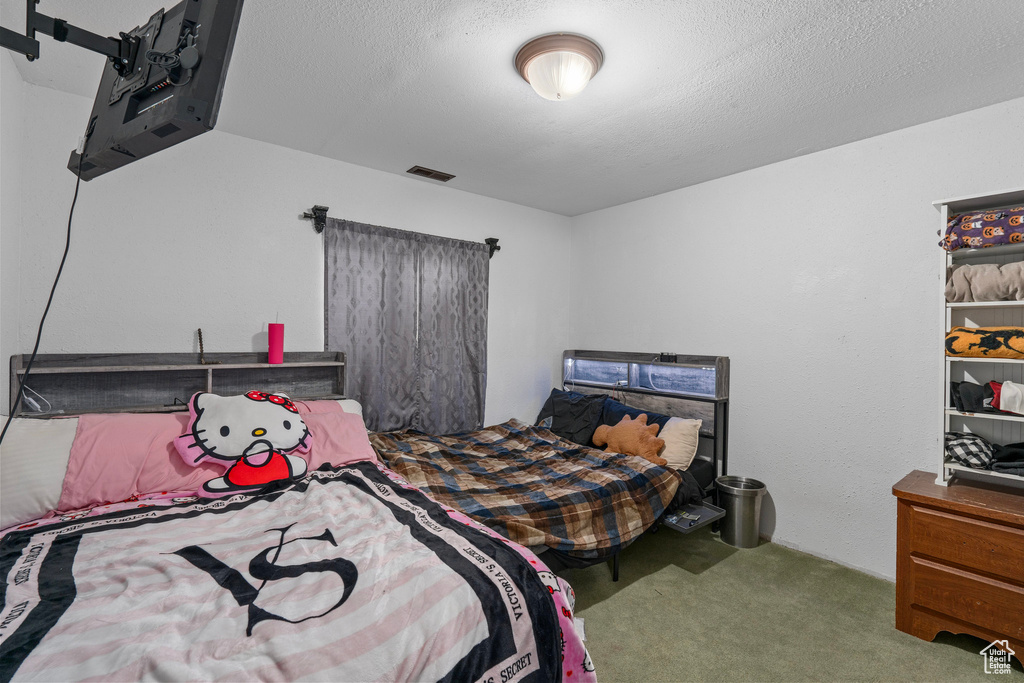 Carpeted bedroom with visible vents and a textured ceiling