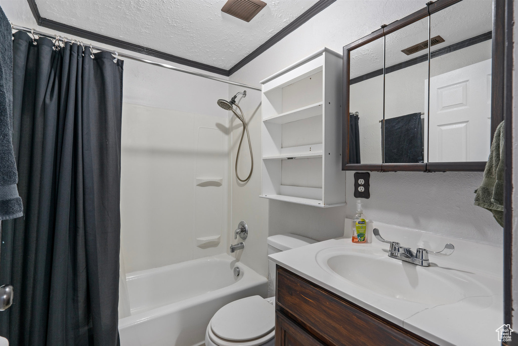 Full bath with crown molding, toilet, vanity, a textured ceiling, and shower / bath combination with curtain