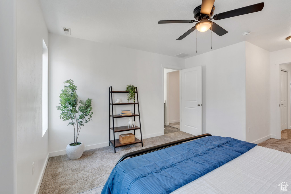 Bedroom featuring light carpet, baseboards, visible vents, and a ceiling fan
