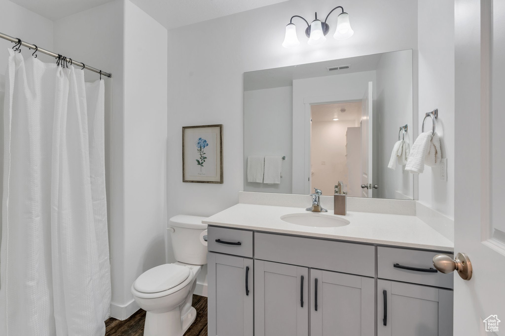 Full bath with visible vents, wood finished floors, toilet, and vanity