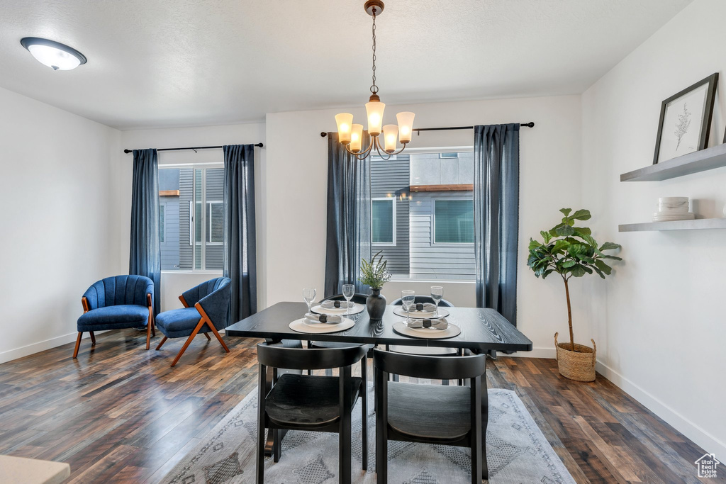 Dining area with an inviting chandelier, plenty of natural light, and dark wood finished floors