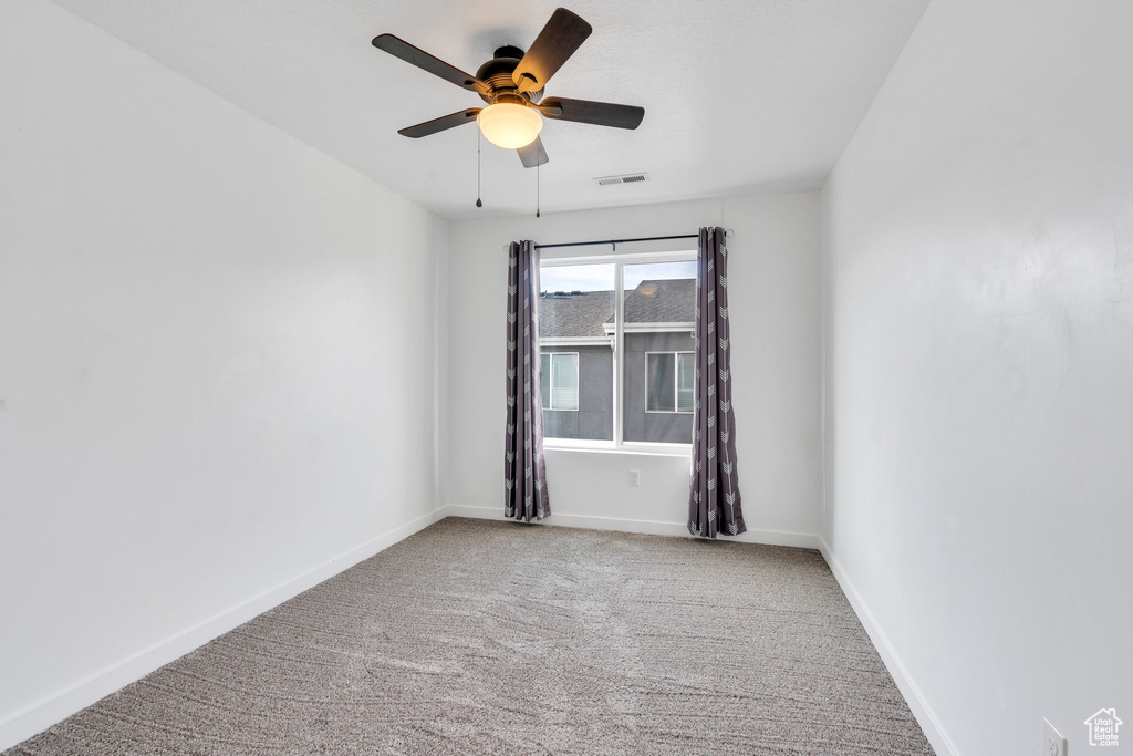 Carpeted spare room featuring a ceiling fan, baseboards, and visible vents