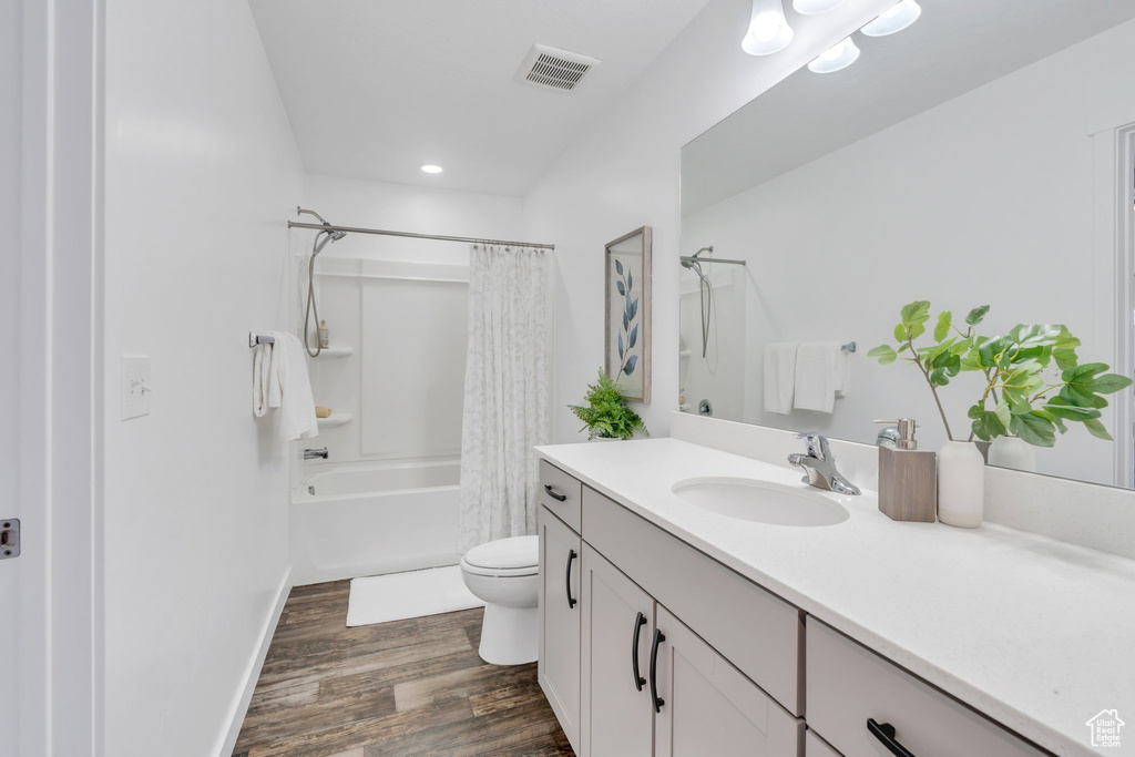 Bathroom featuring vanity, toilet, visible vents, shower / bath combination with curtain, and wood finished floors
