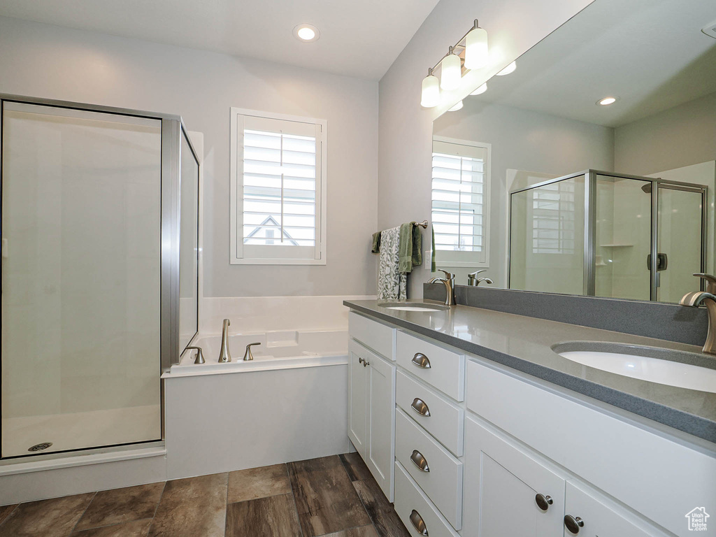 Full bath featuring double vanity, a sink, a stall shower, and a bath