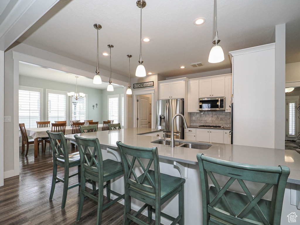 Kitchen with a sink, tasteful backsplash, appliances with stainless steel finishes, white cabinets, and dark wood-style flooring