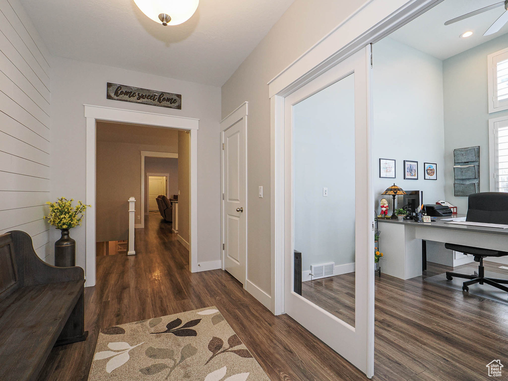 Hall with baseboards, visible vents, and wood finished floors