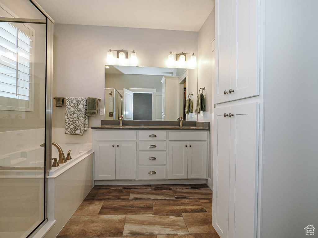 Bathroom with a garden tub, double vanity, a sink, and a stall shower