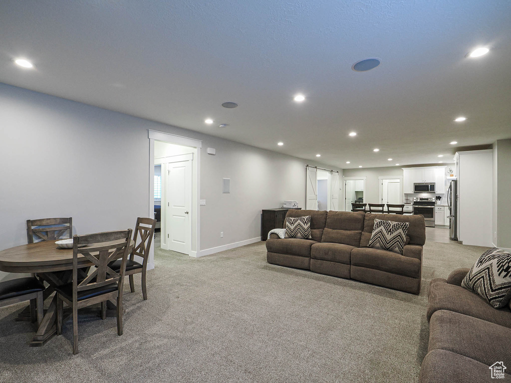 Living room with light colored carpet, baseboards, and recessed lighting
