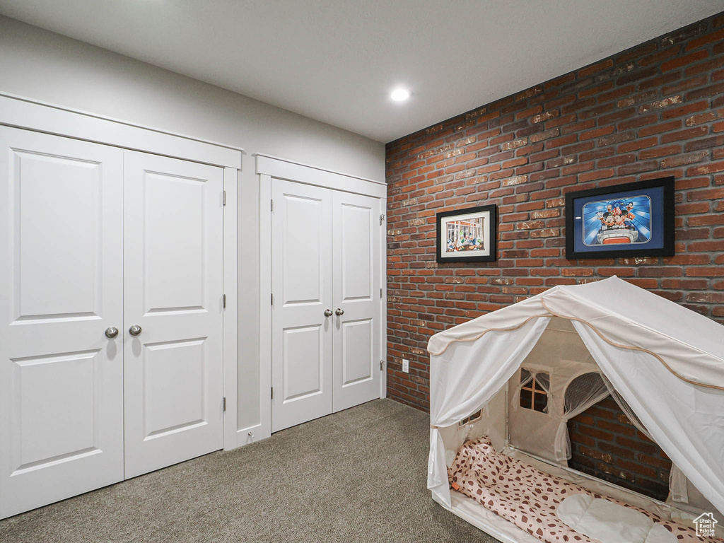 Bedroom featuring multiple closets, recessed lighting, carpet, and brick wall