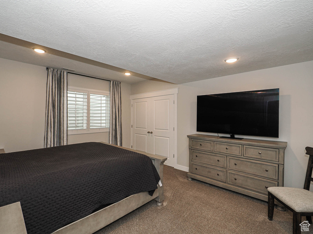 Bedroom with a textured ceiling, recessed lighting, and dark colored carpet