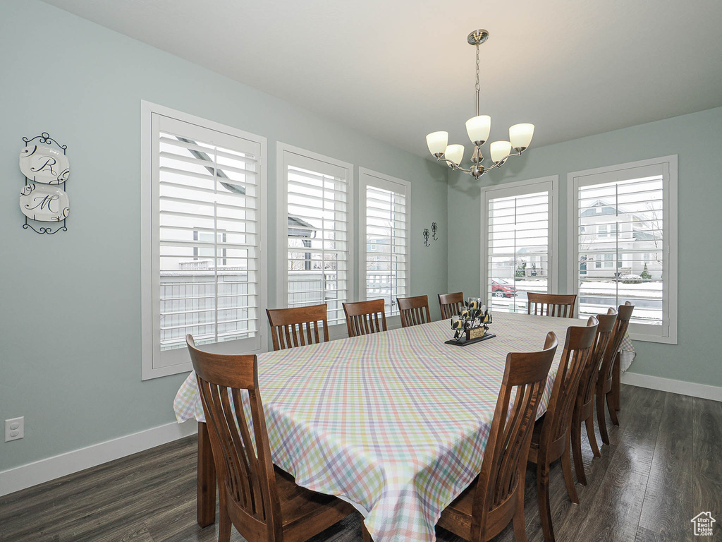 Dining room with dark wood-style floors, baseboards, and an inviting chandelier